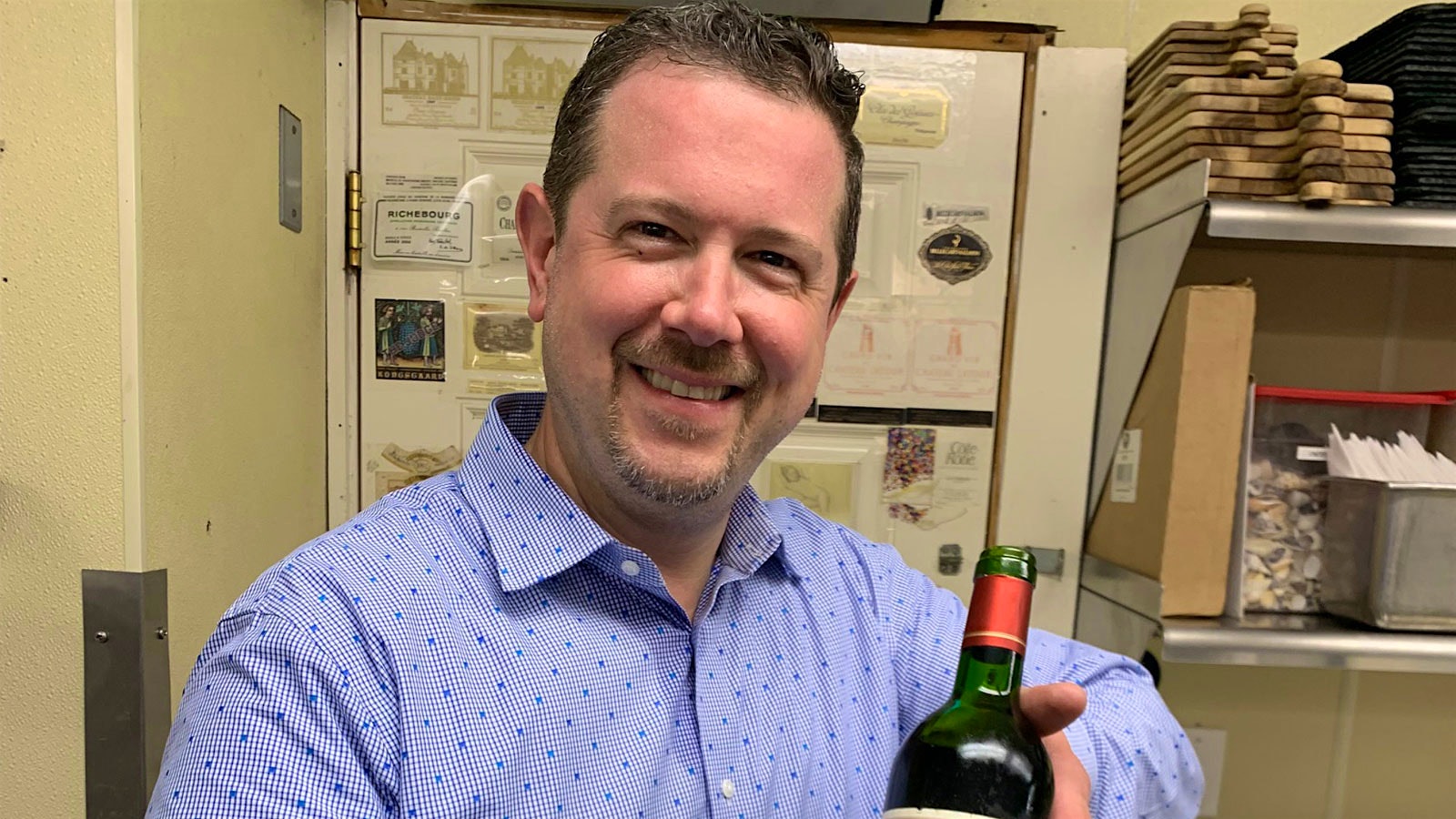 Portrait of Jason Irving holding a bottle of wine.